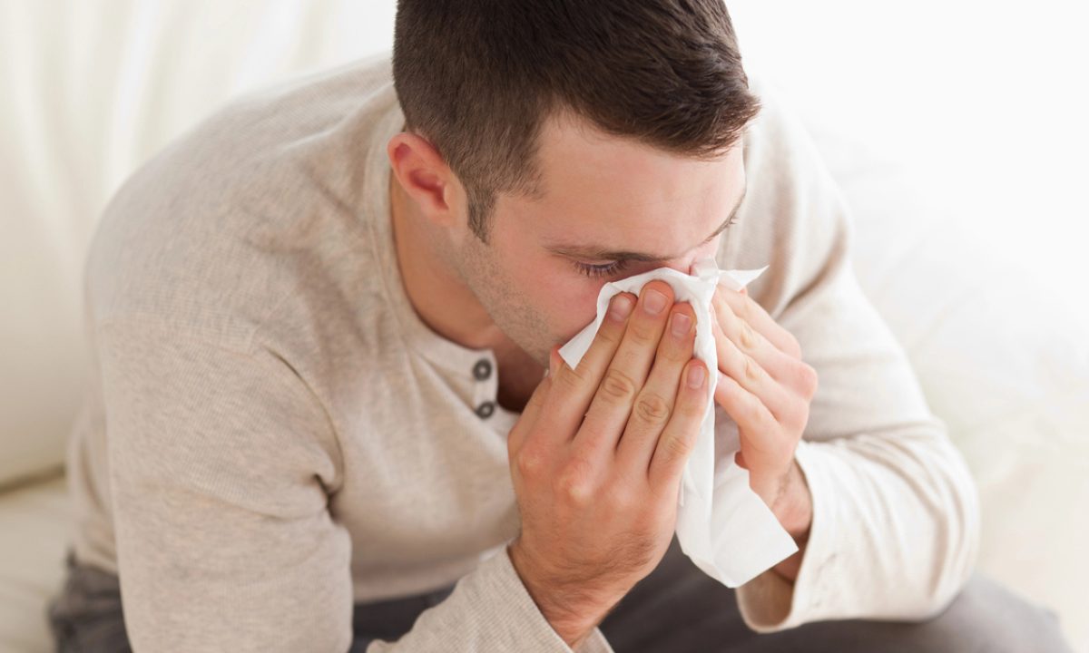 Ill man blowing his nose in his living room