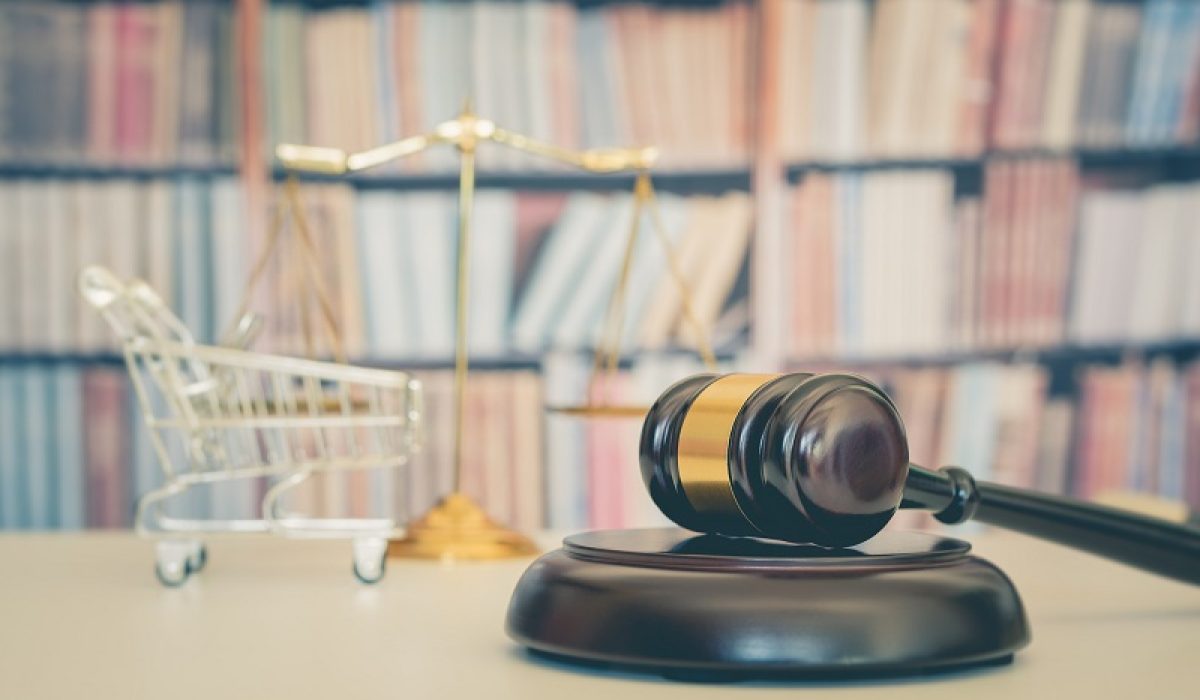 Consumer rights and consimer protection, business law concept : Wooden judge gavel, a shopping cart, a balanced scale of justice on a table, depicting the practice of safeguarding buyers of goods and services.